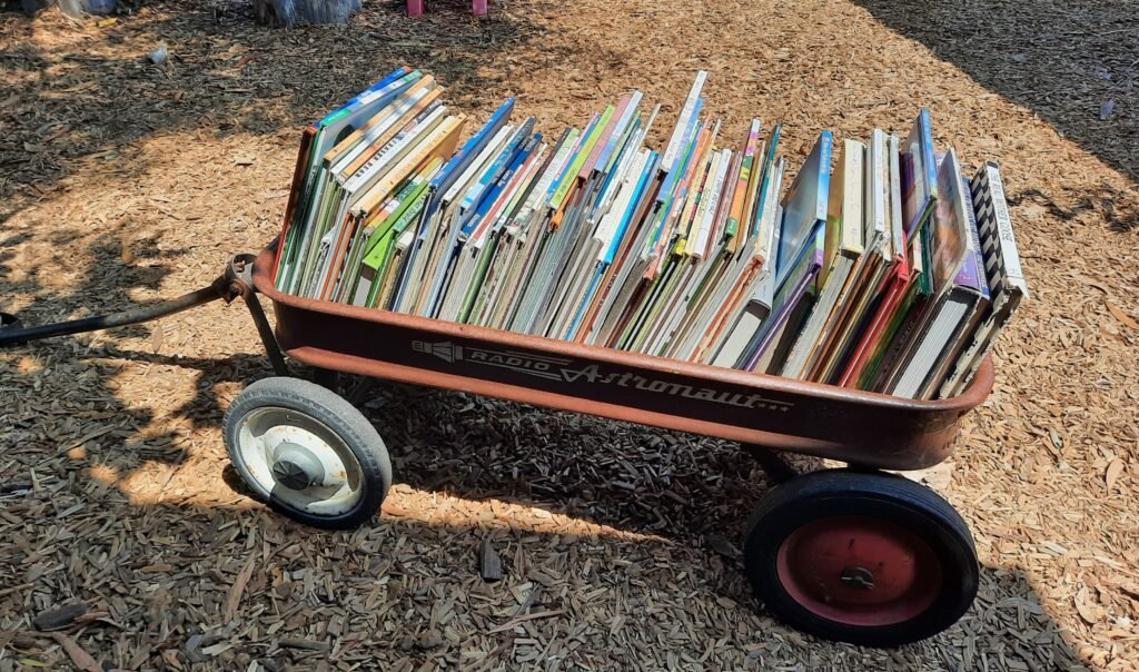 Red Radio Astronaut wagon filled with children’s books outdoors, ready for storytime in a nature-based learning environment